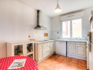 a kitchen with white cabinets and a red table at Apartment les Terrasses du Cap by Interhome in Capbreton