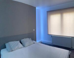 - une chambre avec un lit blanc et une grande fenêtre dans l'établissement Beach apartment, à Coxyde
