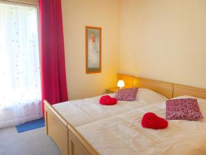 - une chambre avec 2 lits dotés d'oreillers rouges et d'une fenêtre dans l'établissement Apartment Le Petit Robinson-4 by Interhome, à La Richardais