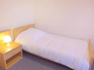 een slaapkamer met een bed en een nachtkastje met een witte sprei bij Apartment Le Petit Robinson-3 by Interhome in La Richardais +13 foto's