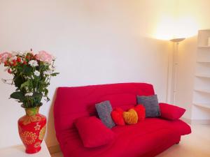 - un canapé rouge avec des oreillers colorés et un vase avec des fleurs dans l'établissement Apartment Le Petit Robinson-6 by Interhome, à La Richardais