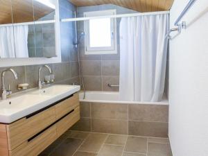 ein Badezimmer mit einem Waschbecken, einer Badewanne und einer Dusche in der Unterkunft Holiday Home Chalet Reinhysi by Interhome in Grindelwald