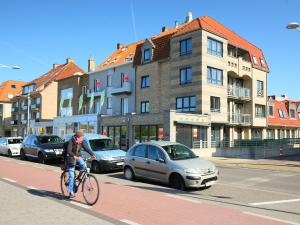 Um homem a andar de bicicleta numa rua com carros. em Apartment Residentie Maritiem by Interhome em Bredene