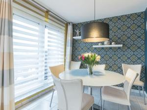 uma sala de jantar com uma mesa com cadeiras e um vaso de flores em Apartment Residentie Maritiem by Interhome em Bredene
