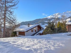 uma casa na neve com montanhas ao fundo em Studio Diure 0113 by Interhome em Verbier