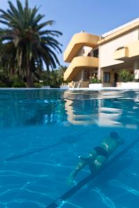 a person swimming in a swimming pool next to a building at Hotel Fortezza in Arborea