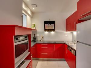 Il comprend une cuisine avec des placards rouges et une télévision murale. dans l'établissement Holiday Home Bon Port by Interhome, à Saint-Philibert