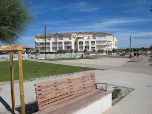 a wooden bench in front of a large building at Apartment Grand Pavois-5 by Interhome in Mimizan-Plage