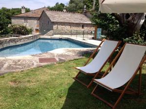 two chairs and an umbrella next to a swimming pool at Fervenza Casa Grande & Restaurante in Reguengo