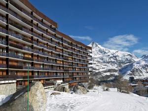 een groot gebouw met een met sneeuw bedekte berg op de achtergrond bij Apartment Le Bec Rouge - Le Lac-5 by Interhome in Tignes