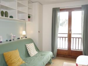 a living room with a green couch and a sliding glass door at Studio Le Sapin-1 by Interhome in Demi-Quartier