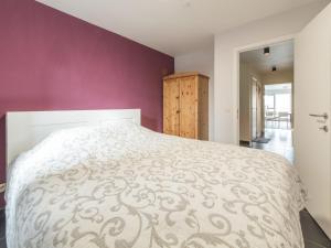 a bedroom with a white bed with a purple wall at Apartment Residentie Albatros by Interhome in Bredene