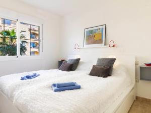 a large white bed with two blue pillows on it at Apartment Parque Central by Interhome in Estepona