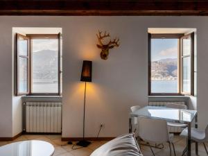 a living room with a table and chairs and windows at Apartment Isola by Interhome in Orta San Giulio