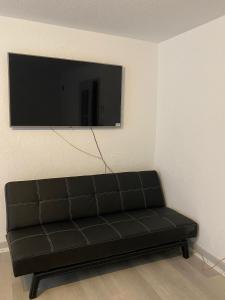 Sofá negro en una habitación con TV de pantalla plana en Private Studio Apartment in Bremgarten, en Bremgarten