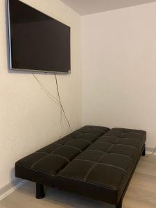 Private Studio Apartment in Bremgarten في بريمغارتين: أريكة سوداء مع تلفزيون بشاشة مسطحة على الحائط