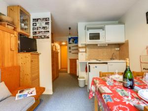 a small kitchen with a table with a bottle of wine at Apartment Les Olympiques-10 by Interhome in Les Boisses