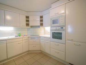 cocina blanca con armarios blancos y microondas en Apartment Bergere-1 by Interhome en Zermatt