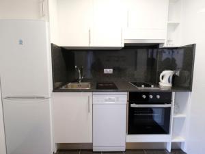 a kitchen with white cabinets and a sink and a stove at Apartment Formentor II by Interhome in Salou