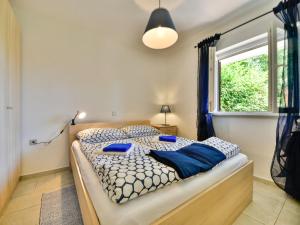 - une chambre avec un lit doté d'oreillers bleus et d'une fenêtre dans l'établissement Apartment Beni-2 by Interhome, à Matulji