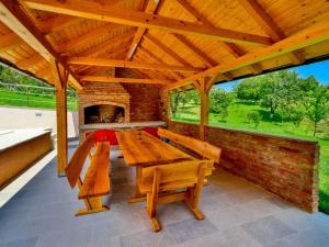 einen Holztisch und Bänke auf einer Terrasse mit Kamin in der Unterkunft Holiday Home Madera by Interhome in Banjaselo