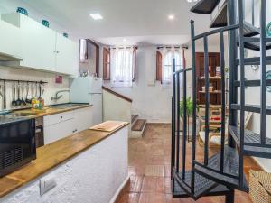 a kitchen with white cabinets and a spiral staircase at Holiday Home Cueva de Lindaraja by Interhome in Granada