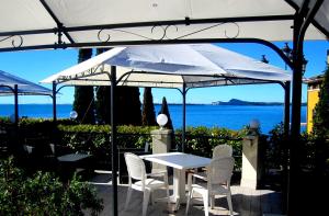 ein weißer Tisch und Stühle unter einem weißen Sonnenschirm in der Unterkunft Edonè Al Lago in Gardone Riviera
