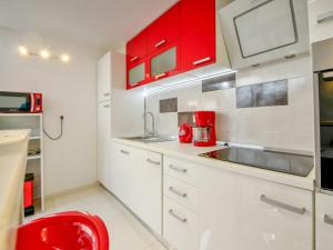una cocina blanca con armarios rojos y una silla roja en Holiday Home Lana 1 by Interhome, en Matulji
