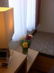 eine Vase mit Blumen auf einem Tisch neben einem Bett in der Unterkunft Gasthof Teufl in Purgstall