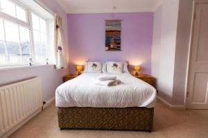 una camera da letto con pareti viola e un letto con due lampade di Oak House in Mid Wales By Seren Short Stays a Machynlleth