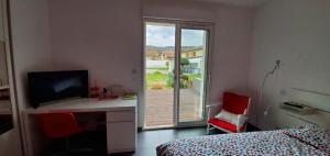 a bedroom with a bed and a desk with a television at Chez Anne Marie in Beausemblant