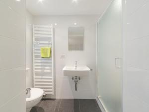 La salle de bains blanche est pourvue de toilettes et d'un lavabo. dans l'établissement Apartment Littoral by Interhome, au Coq