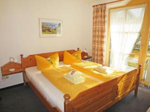 a bedroom with a large wooden bed with yellow pillows at Apartment Wohnung 4 - Am Sonneneck by Interhome in Ruhpolding