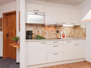 a white kitchen with white cabinets and appliances at Apartment Wohnung 4 - Am Sonneneck by Interhome in Ruhpolding