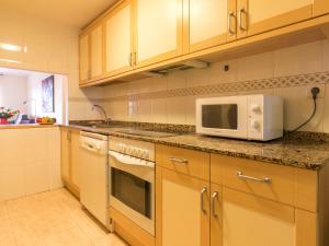 cocina con armarios de madera y microondas en Apartment Monaco by Interhome, en Cambrils