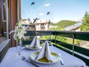 a table with two plates and a vase of flowers on a balcony at Apartment Chesa Corvatsch 111 - Champfer by Interhome in Surlej