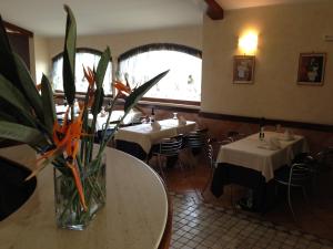 restauracja ze stołami i wazonem kwiatów na stole w obiekcie La Locanda del Cavaliere w mieście Borgo Montello