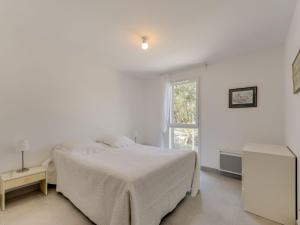 a white bedroom with a bed and a window at Apartment 79 Bay-2 by Interhome in Cavalaire-sur-Mer