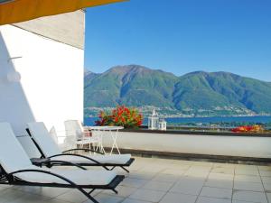 uma varanda com 2 cadeiras, uma mesa e montanhas em Apartment Residenza Solemonte by Interhome em Locarno