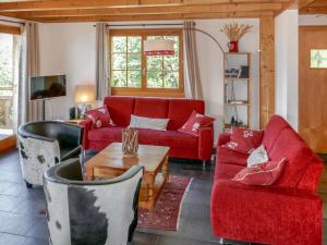 a living room with two red couches and a table at Chalet Le Muveran V6 by Interhome in Nendaz