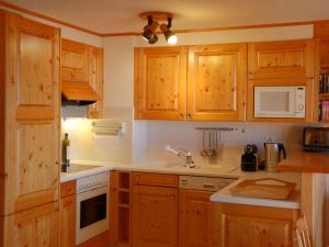 uma cozinha com armários de madeira, um lavatório e um micro-ondas em Apartment Mandarin 7 by Interhome em Villars-sur-Ollon