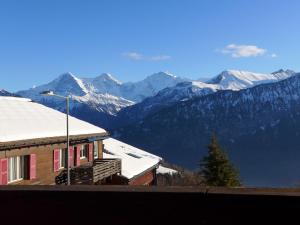 a house with snow covered mountains in the background at Apartment Chalet Burgfeld by Interhome in Beatenberg