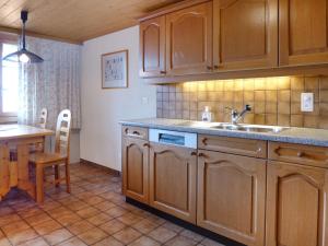 a kitchen with wooden cabinets and a sink and a table at Apartment Chalet Burgfeld by Interhome in Beatenberg