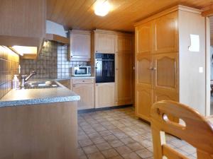 a kitchen with wooden cabinets and a sink and a microwave at Apartment Chalet Burgfeld by Interhome in Beatenberg +18 photos