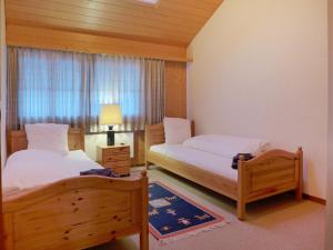 a bedroom with two beds and a window at Apartment Chalet Burgfeld by Interhome in Beatenberg