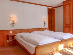 a bed in a room with two lamps on the wall at Apartment Casa Pia-2 by Interhome in Zermatt