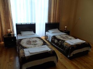 two beds sitting in a room with a window at Jahongir B&B Tashkent in Tashkent