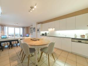 a kitchen and dining room with a wooden table and chairs at Apartment D'Heyezicht with parking by Interhome in Bredene