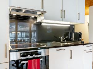 La cuisine est équipée de placards blancs et d'un four avec plaques de cuisson. dans l'établissement Apartment Tasman S16-2 by Interhome, au Bouveret
