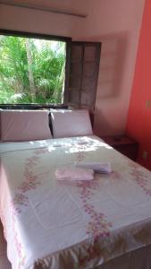 a bedroom with a bed with a window and flowers on it at Okakoaras Hotel in Maria Farinha